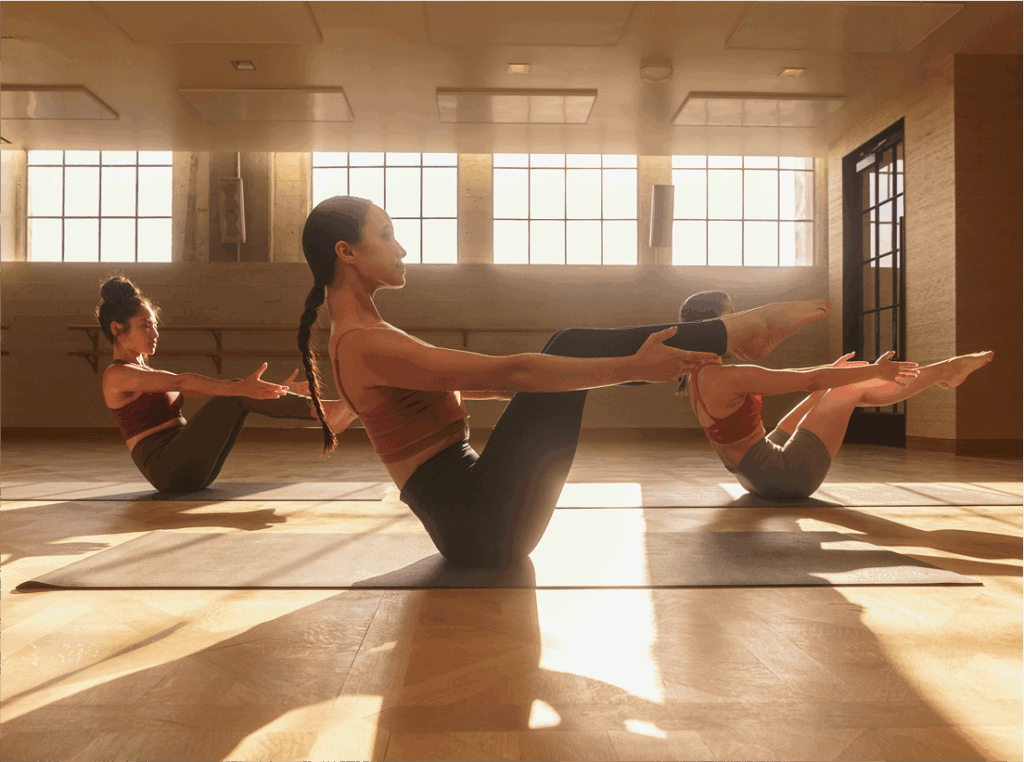 Women holding core poses in a sunlit Heimat movement studio.